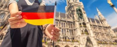 Person standing outside a building holding a German flag.